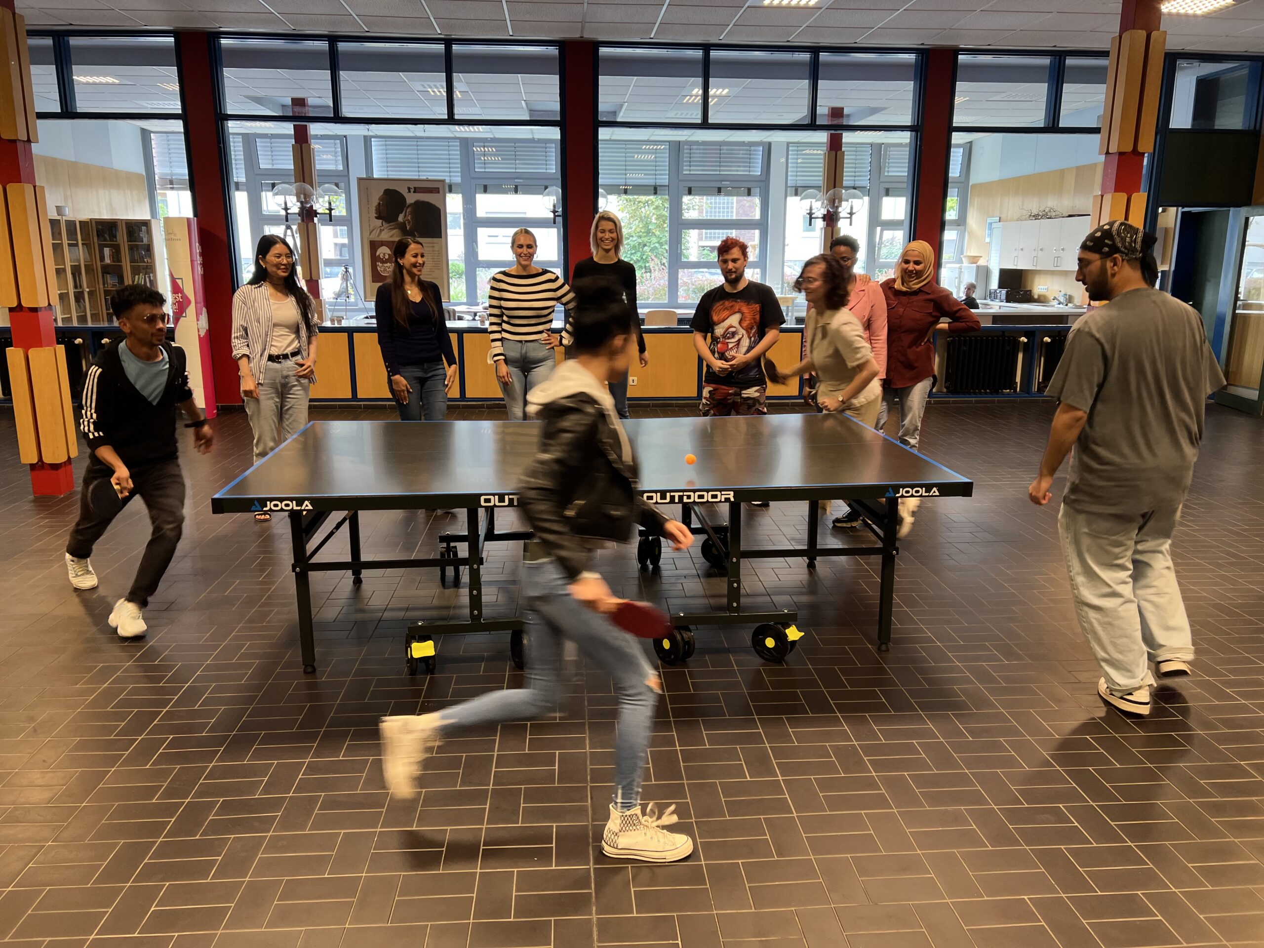 Studierende spielen in der Schulaula Tischtennis.