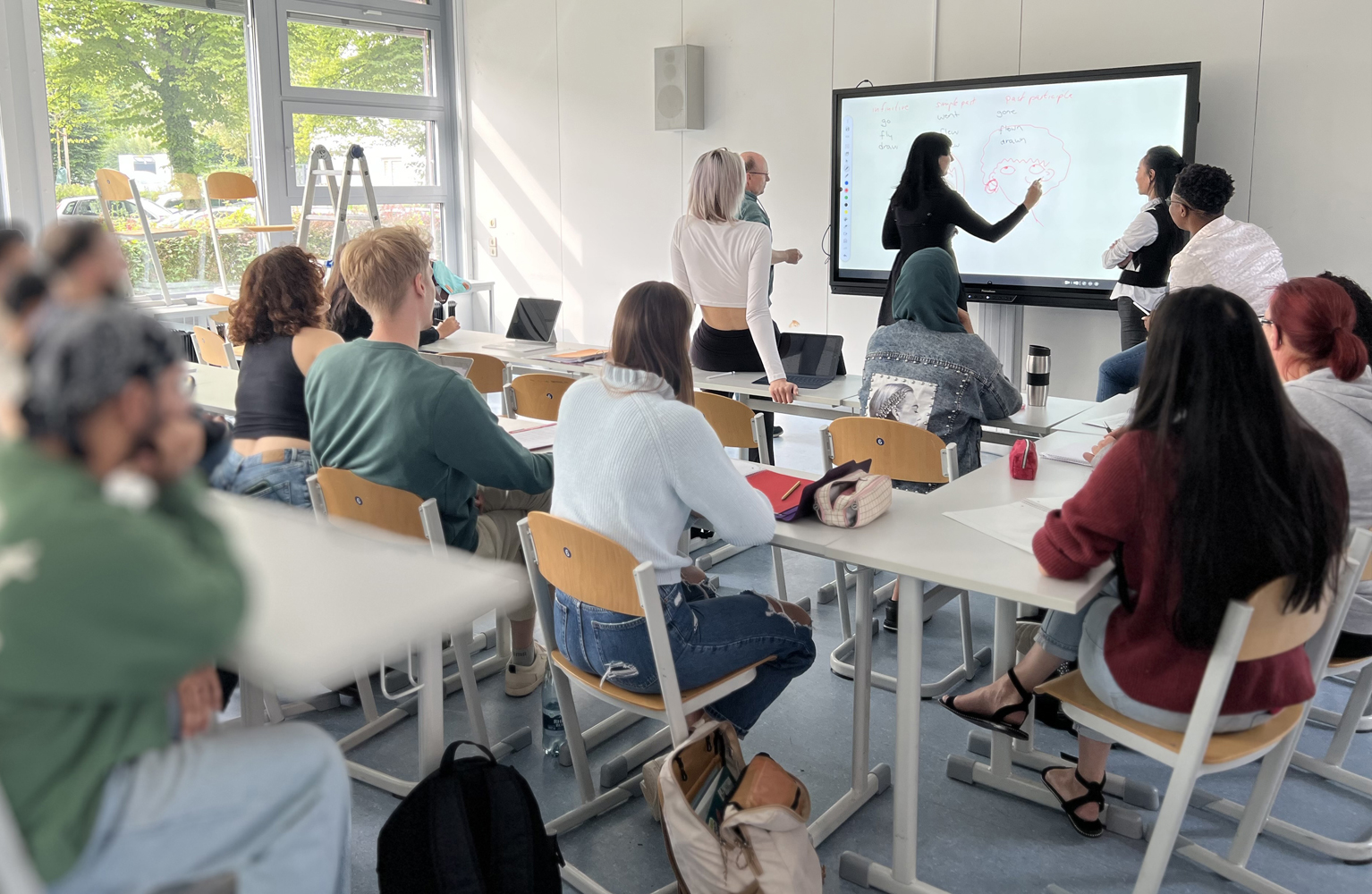 Klassenraum mit Studierenden vor einer elektronischen Tafel