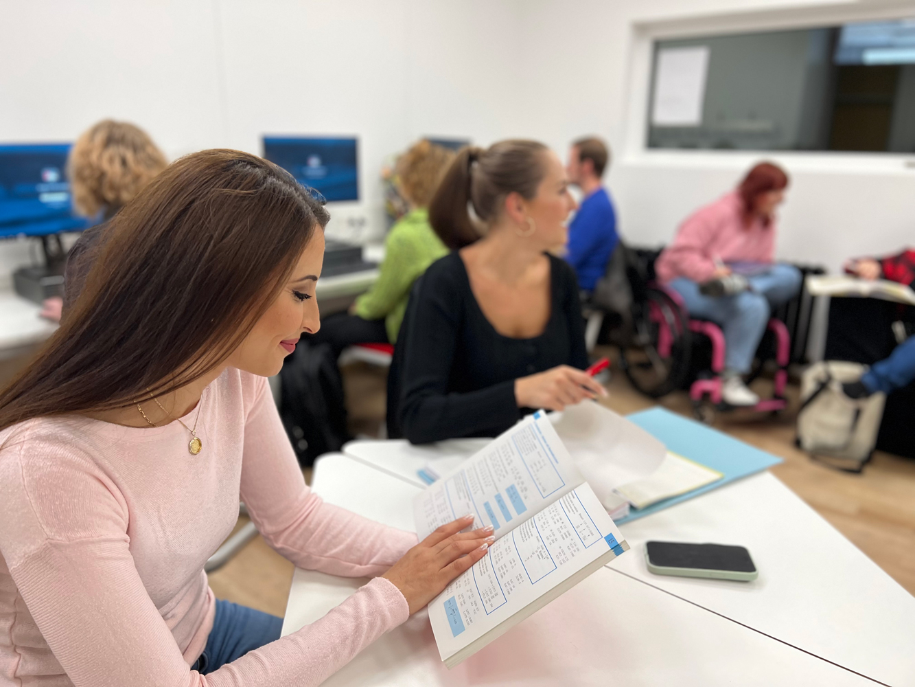 Mehrere Studierende sitzen im Selbstlernzentrum zusammen lernend an einem Tisch.